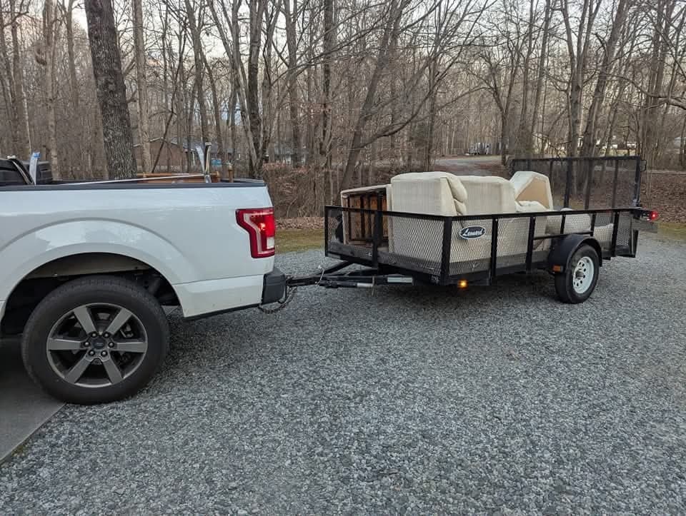 Smaller utility trailer staged with a sofa and living room pieces ready to be secured.